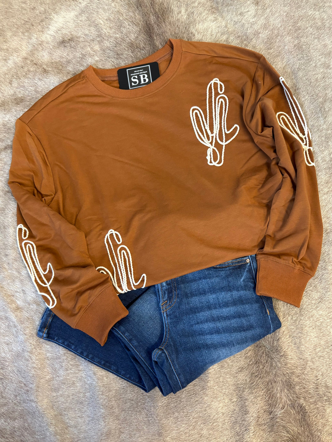 Rust-colored unlined sweatshirt with white embroidered cactus details, made from super-soft fabric.