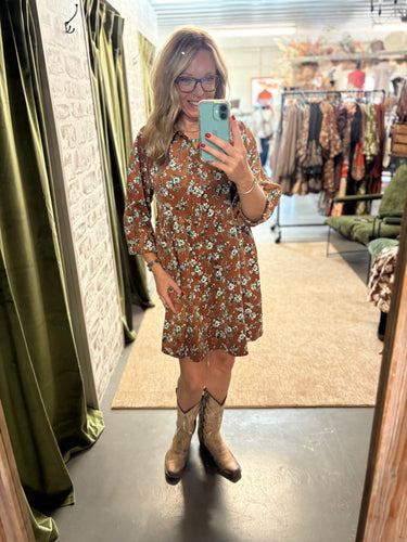 Woman wearing The Rust Blossom Corduroy Dress—floral baby corduroy, button-down, with pockets, styled with cowgirl boots.