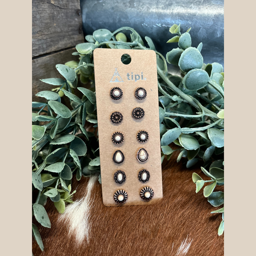 Six small copper stud earrings with white stones.