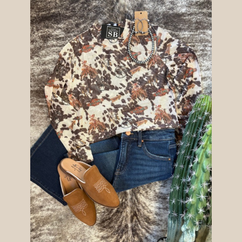 Cowhide print mesh top with western rodeo motifs, styled with dark denim jeans and camel western mules.