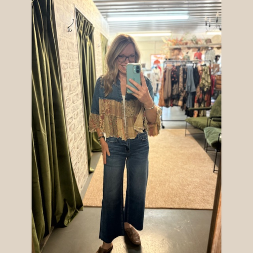 Woman wearing denim patchwork jacket with earthy prints, raw hem, and flowy sleeves.