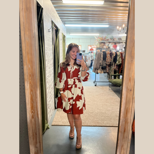 Rust dress with cream floral print, split neckline with top tie, three-quarter sleeves, and pockets.