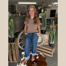 Load image into Gallery viewer, Woman wearing the Prairie Ribbed Top in mocha with turquoise jewelry, standing in front of a rustic wooden wagon.

