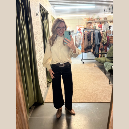 Woman wearing Prairie Grace Ruffle Blouse, standing in boutique dressing room.