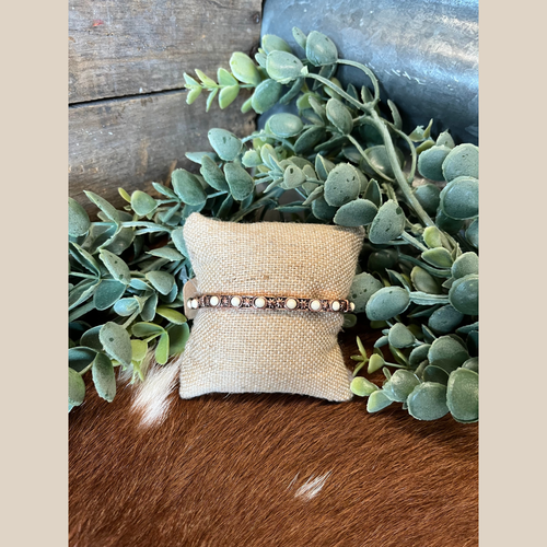 Copper stretch bracelet featuring round white stones and concho designs.
