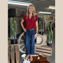 Load image into Gallery viewer, Woman wearing the Split Neck Short Sleeve Pullover in red with denim, standing in front of a rustic wooden wagon.
