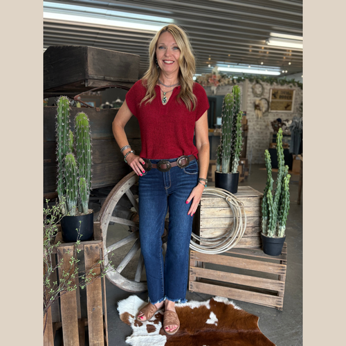 Woman wearing the Split Neck Short Sleeve Pullover in red with denim, standing in front of a rustic wooden wagon.