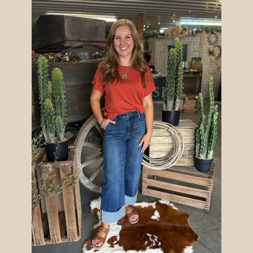 Woman wearing an incredibly soft terracotta short sleeve sweater, styled for fall in a cozy western-inspired indoor setting.