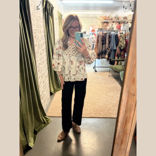 Woman wearing Wildflower Prairie Blouse, standing in boutique dressing room. 